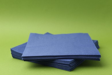 Photo of Stack of blue handkerchiefs on green background, closeup. Space for text