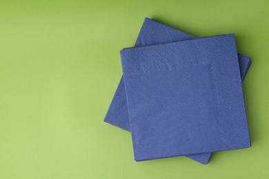Photo of Stack of blue handkerchiefs on green background, top view. Space for text