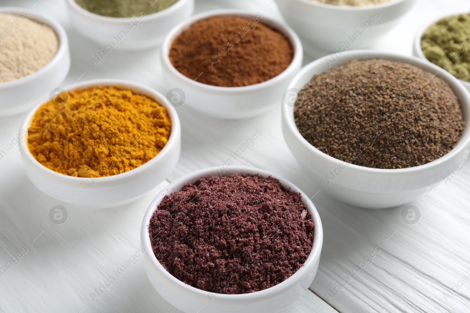 Different superfood powders in bowls on white wooden table, closeup Photo of Different superfood powders in bowls on white wooden table, closeup