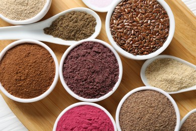 Photo of Different superfoods in bowls and spoons on table, top view