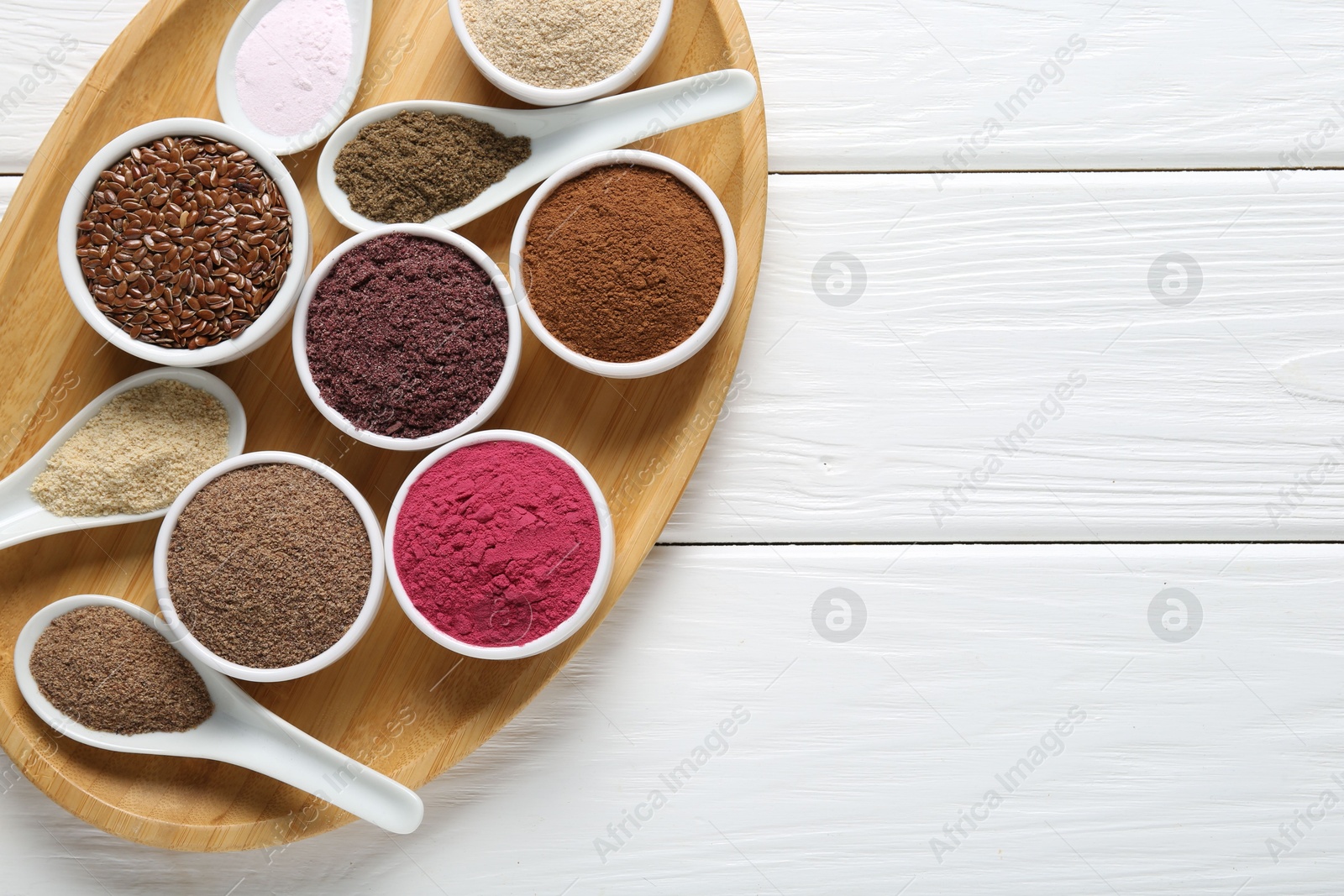 Different superfoods in bowls and spoons on white wooden table, top view. Space for text Photo of Different superfoods in bowls and spoons on white wooden table, top view. Space for text