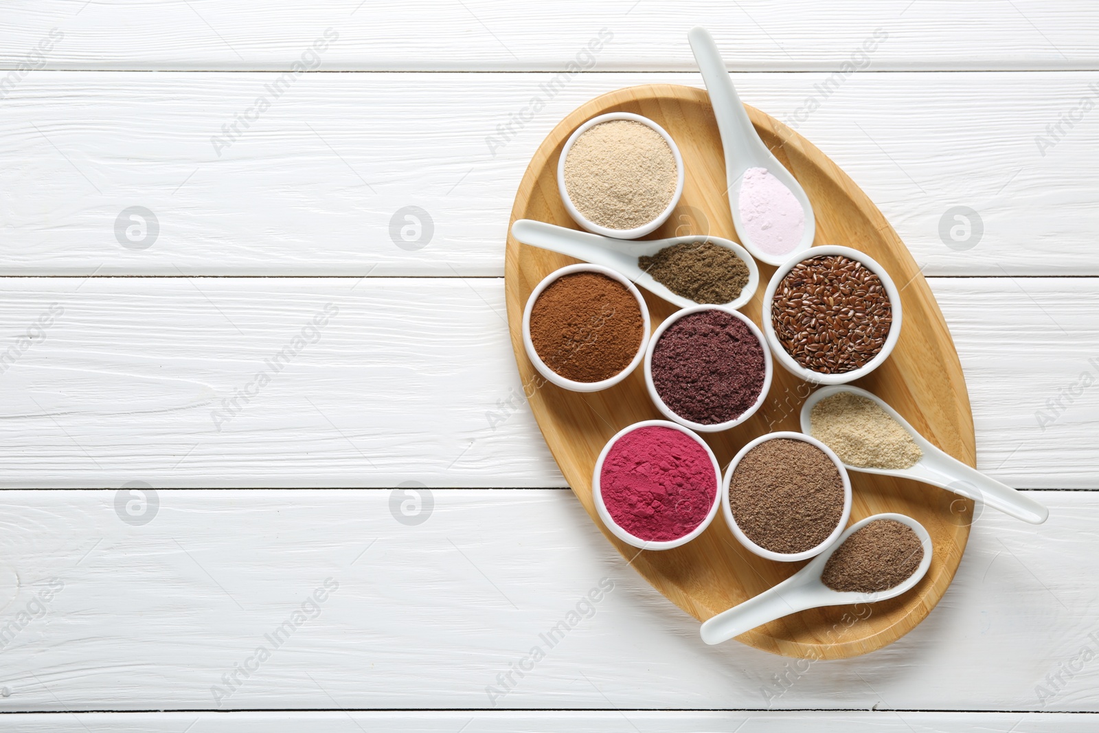 Different superfoods in bowls and spoons on white wooden table, top view. Space for text Photo of Different superfoods in bowls and spoons on white wooden table, top view. Space for text