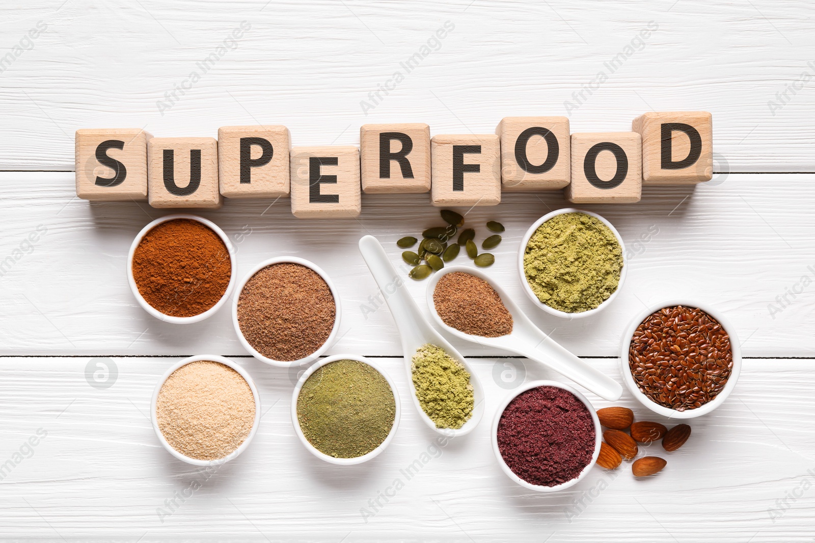 Different superfoods and word made of cubes on white wooden table, flat lay Photo of Different superfoods and word made of cubes on white wooden table, flat lay