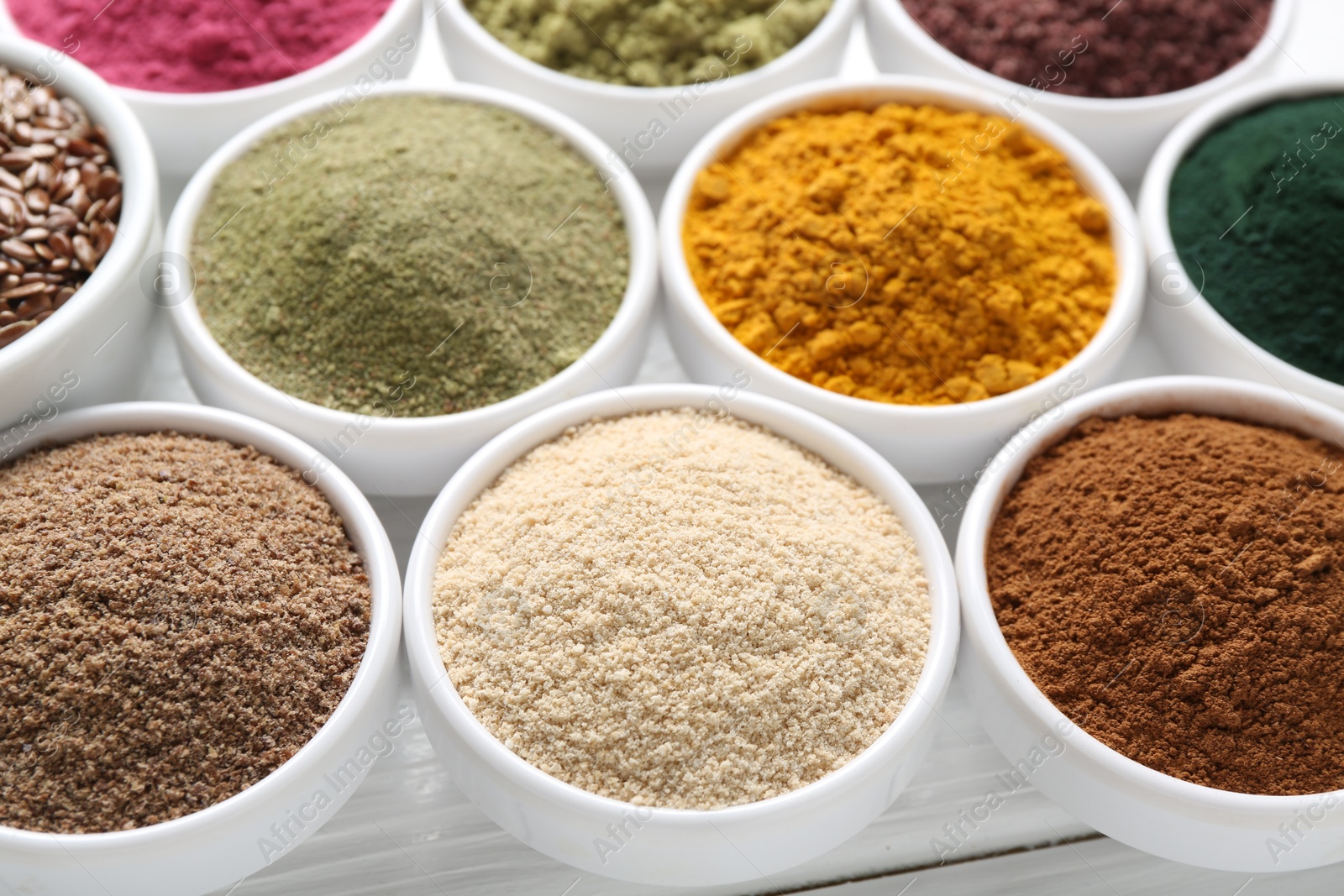 Different superfood powders in bowls on white wooden table, closeup Photo of Different superfood powders in bowls on white wooden table, closeup