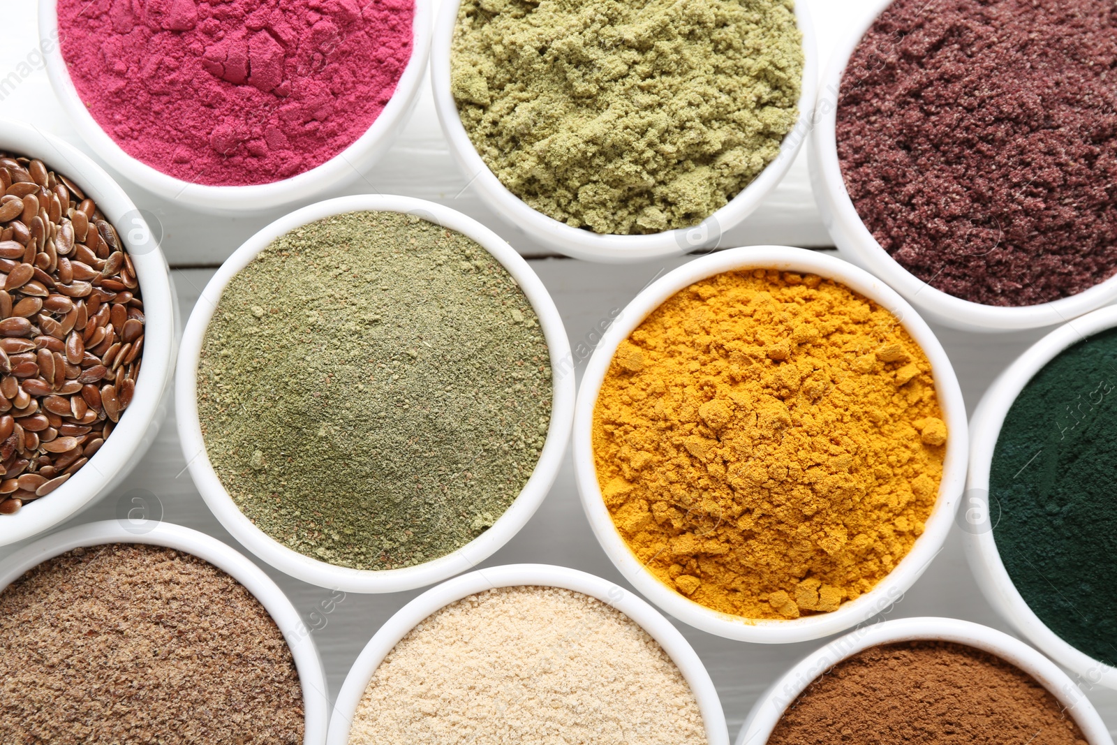 Different superfood powders in bowls on white wooden table, flat lay Photo of Different superfood powders in bowls on white wooden table, flat lay