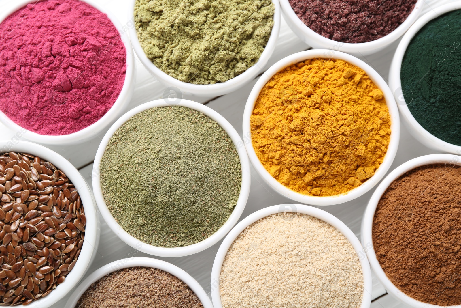 Different superfood powders in bowls on white wooden table, flat lay Photo of Different superfood powders in bowls on white wooden table, flat lay
