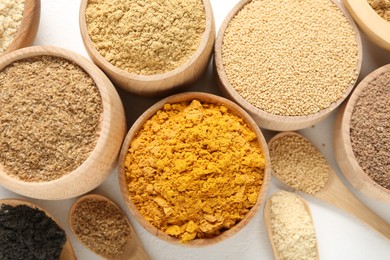 Photo of Different superfood powders in bowls and spoons on white background, flat lay