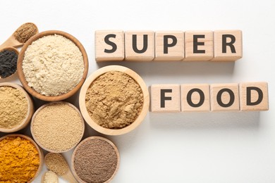 Photo of Different superfoods and words made of wooden cubes on white background, flat lay
