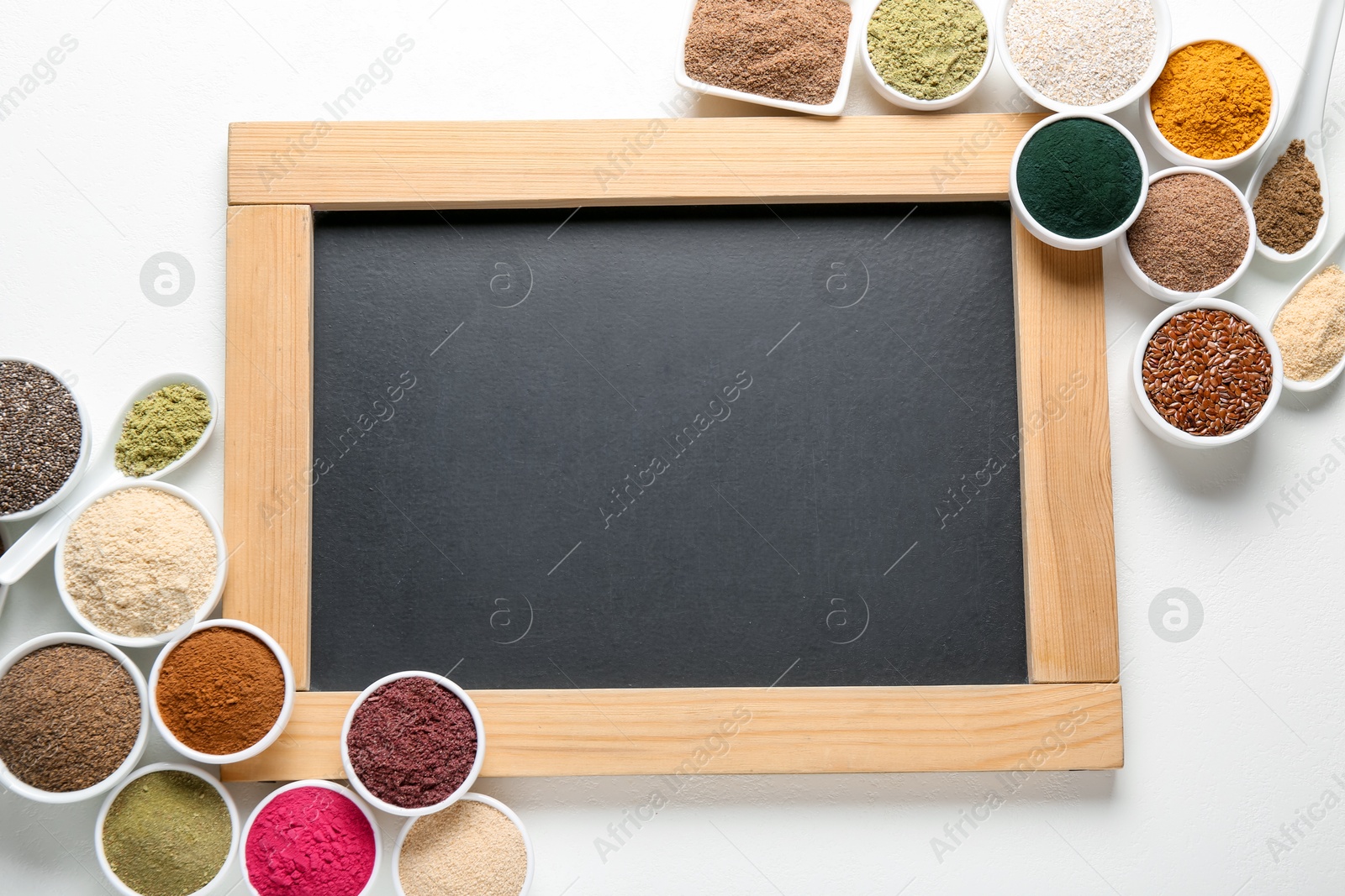 Different superfood products and blank chalkboard on white background, flat lay. Space for text Photo of Different superfood products and blank chalkboard on white background, flat lay. Space for text