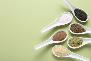 Photo of Different superfood powders in spoons on pale green background, flat lay. Space for text