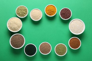 Photo of Frame of different superfood powders in bowls on green background, flat lay. Space for text