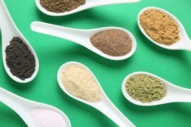 Photo of Different superfood powders in spoons on green background, flat lay