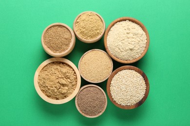 Photo of Different superfood powders in bowls on green background, flat lay