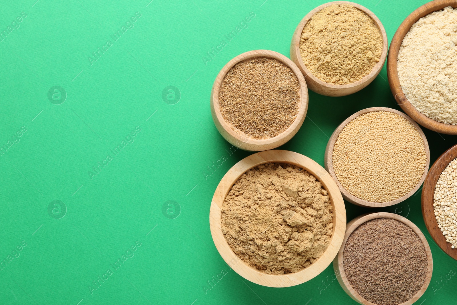 Different superfood powders in bowls on green background, flat lay. Space for text Photo of Different superfood powders in bowls on green background, flat lay. Space for text