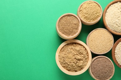 Photo of Different superfood powders in bowls on green background, flat lay. Space for text