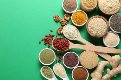 Photo of Different superfood products on green background, flat lay. Space for text