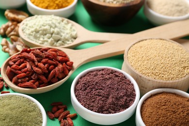 Photo of Different superfood products on green background, closeup