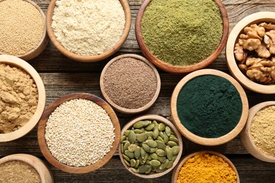 Photo of Different superfoods in bowls on wooden table, flat lay