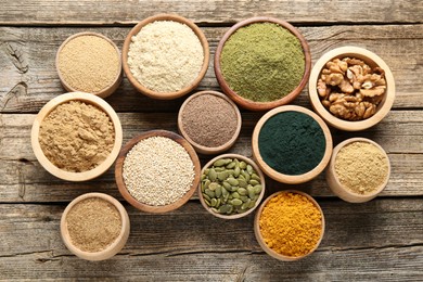 Photo of Different superfoods in bowls on wooden table, flat lay
