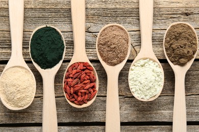 Photo of Different superfoods in spoons on wooden table, flat lay