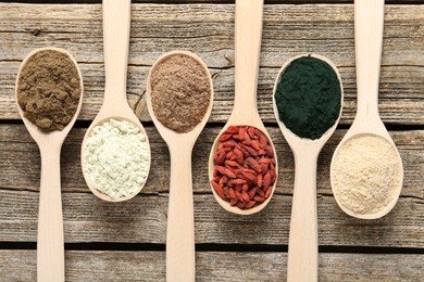 Photo of Different superfoods in spoons on wooden table, flat lay