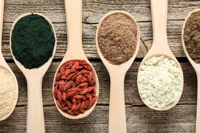 Photo of Different superfoods in spoons on wooden table, flat lay