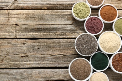 Photo of Different superfoods in bowls on wooden table, flat lay. Space for text
