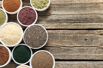 Photo of Different superfoods in bowls on wooden table, flat lay. Space for text