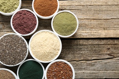 Photo of Different superfoods in bowls on wooden table, flat lay. Space for text