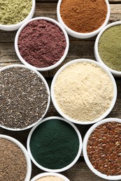 Photo of Different superfoods in bowls on wooden table, flat lay