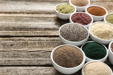 Photo of Different superfoods in bowls on wooden table, closeup. Space for text