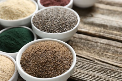 Photo of Different superfoods in bowls on wooden table, closeup. Space for text
