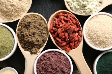 Photo of Different superfoods in spoons and bowls on table, flat lay