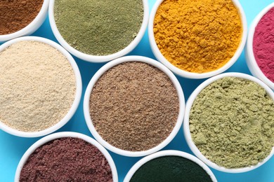 Photo of Different superfood powders in bowls on light blue background, flat lay
