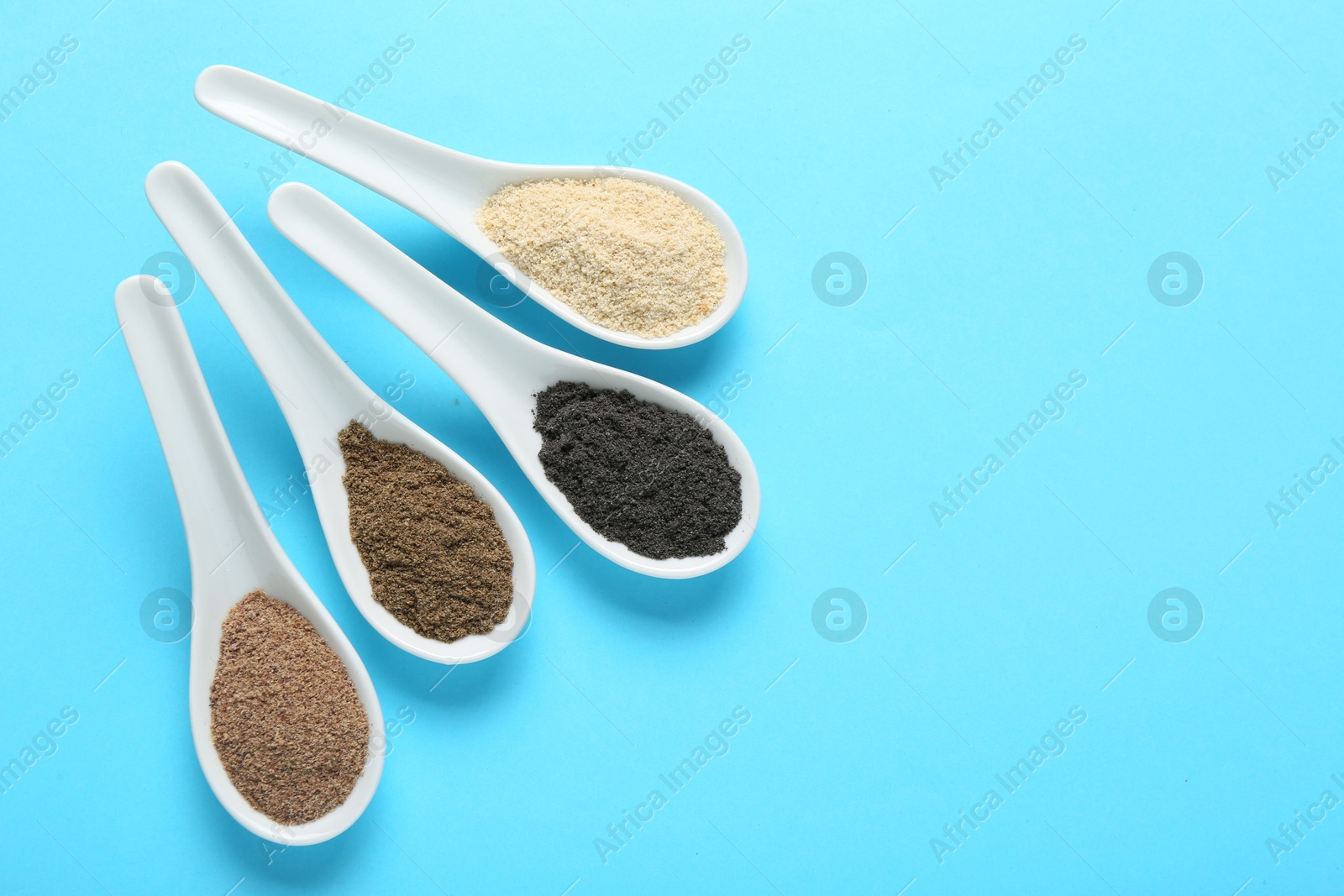 Different superfood powders in spoons on light blue background, flat lay. Space for text Photo of Different superfood powders in spoons on light blue background, flat lay. Space for text