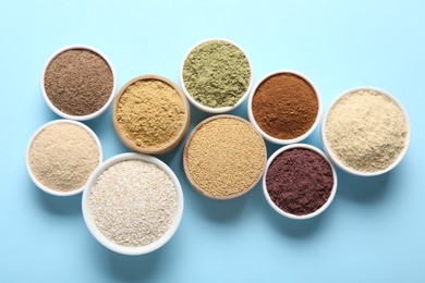 Photo of Different superfood powders in bowls on light blue background, flat lay