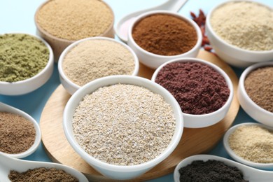 Photo of Different superfood powders on light blue background, closeup