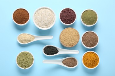 Photo of Different superfood powders in bowls and spoons on light blue background, flat lay