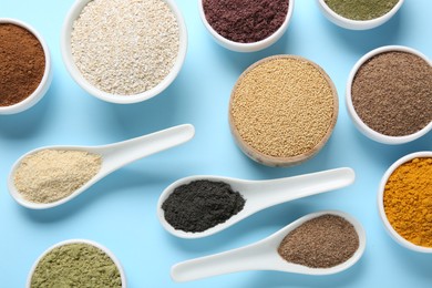 Photo of Different superfood powders in bowls and spoons on light blue background, flat lay