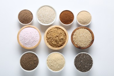 Photo of Different superfood powders in bowls on white background, flat lay