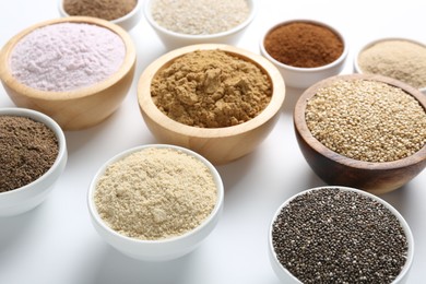Photo of Different superfood powders in bowls on white background, closeup