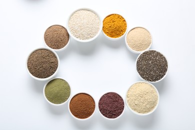 Photo of Frame of different superfood powders in bowls on white background, flat lay. Space for text