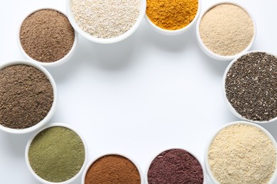 Photo of Frame of different superfood powders in bowls on white background, flat lay. Space for text