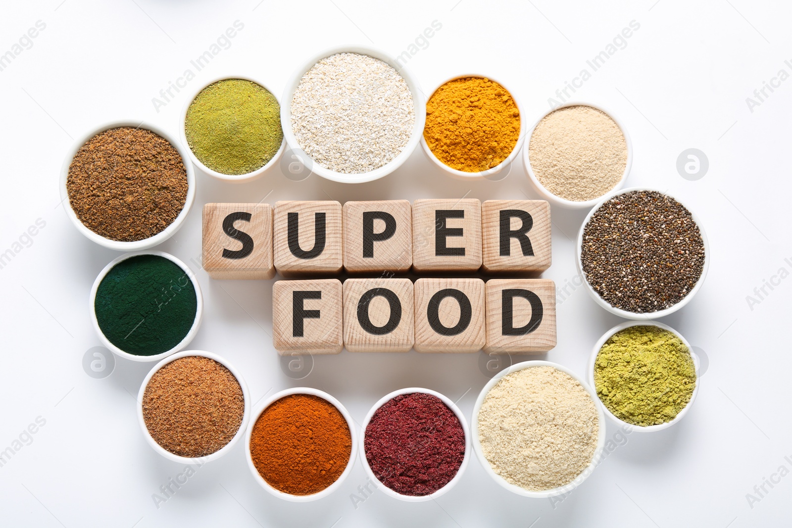 Different superfood powders in bowls and words made of wooden cubes on white background, flat lay Photo of Different superfood powders in bowls and words made of wooden cubes on white background, flat lay