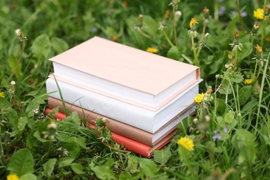 Photo of Stacked books on green grass outdoors, closeup
