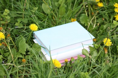 Photo of Stacked books on green grass outdoors, closeup