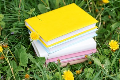 Photo of Stacked books on green grass outdoors, closeup