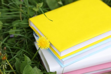 Photo of Stacked books on green grass outdoors, closeup