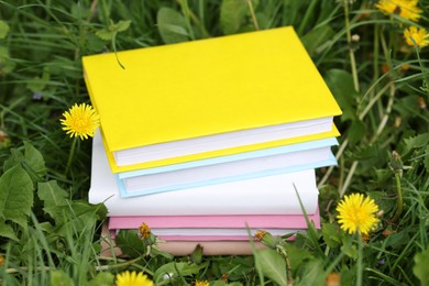 Photo of Stacked books on green grass outdoors, closeup