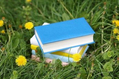 Photo of Stacked books on green grass outdoors, closeup